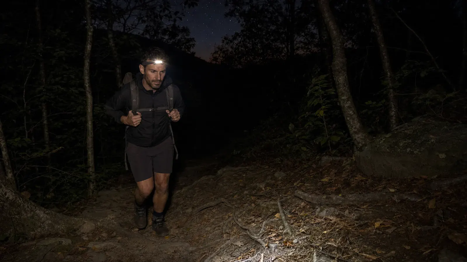 LHKNL rechargeable headlamp being plugged into a USB charging cable on a wooden camp table