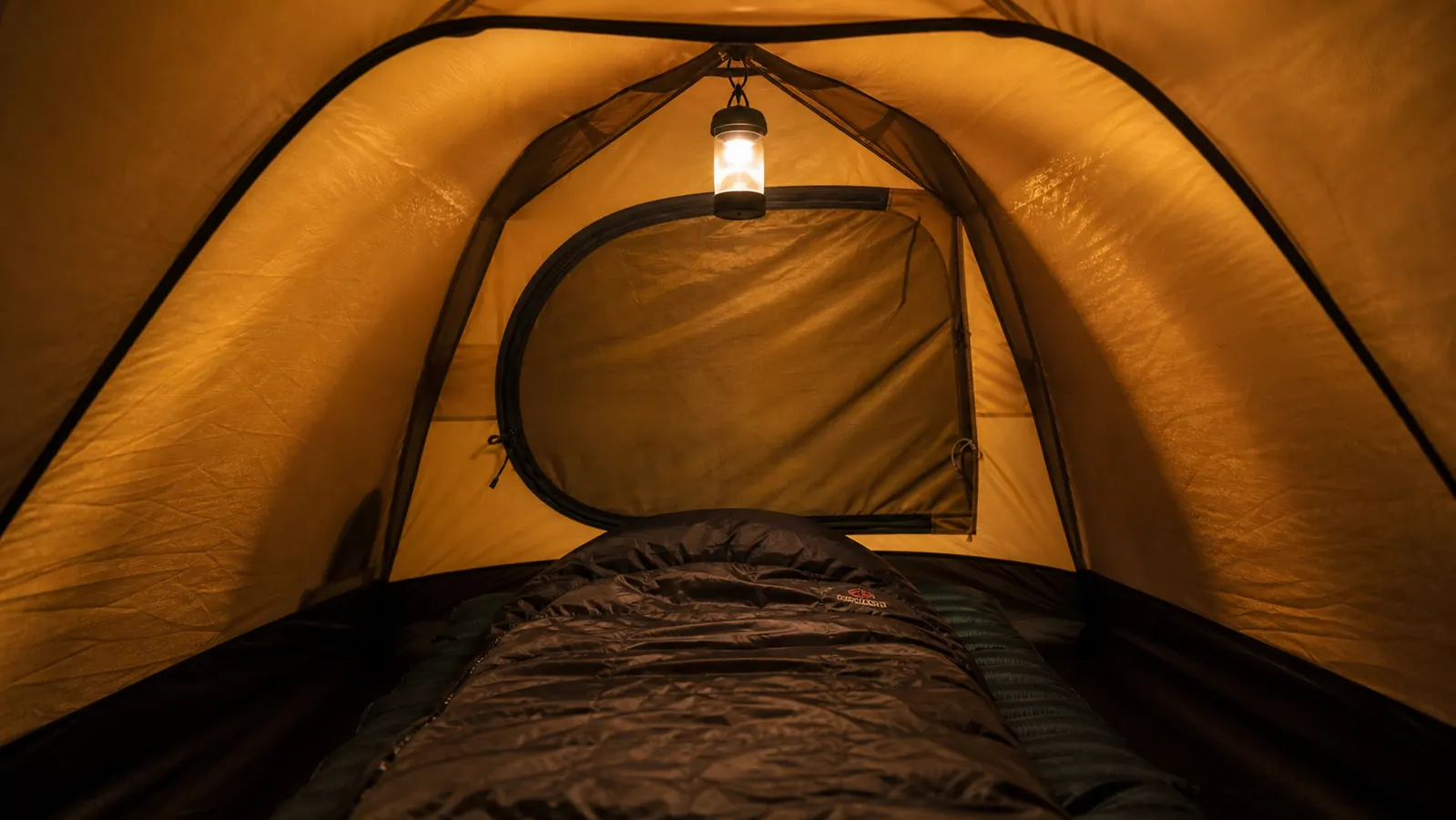 Camper loading gear into the door of a dome tent at a car camping spot