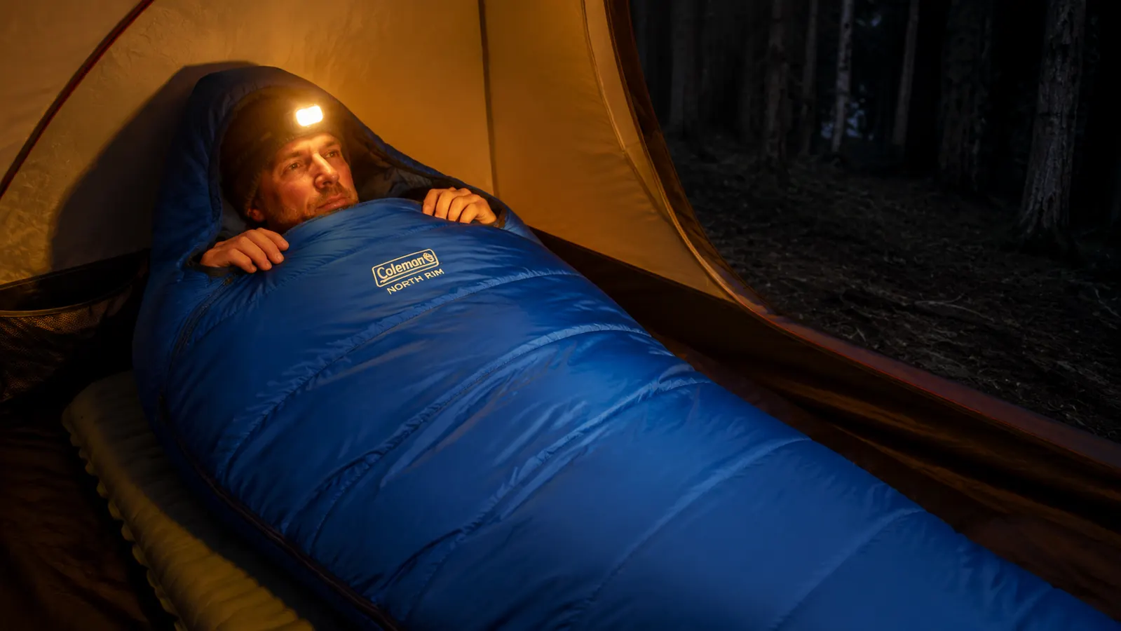 The Coleman North Rim sleeping bag laid out on a camping mat inside a tent with gear organized around it