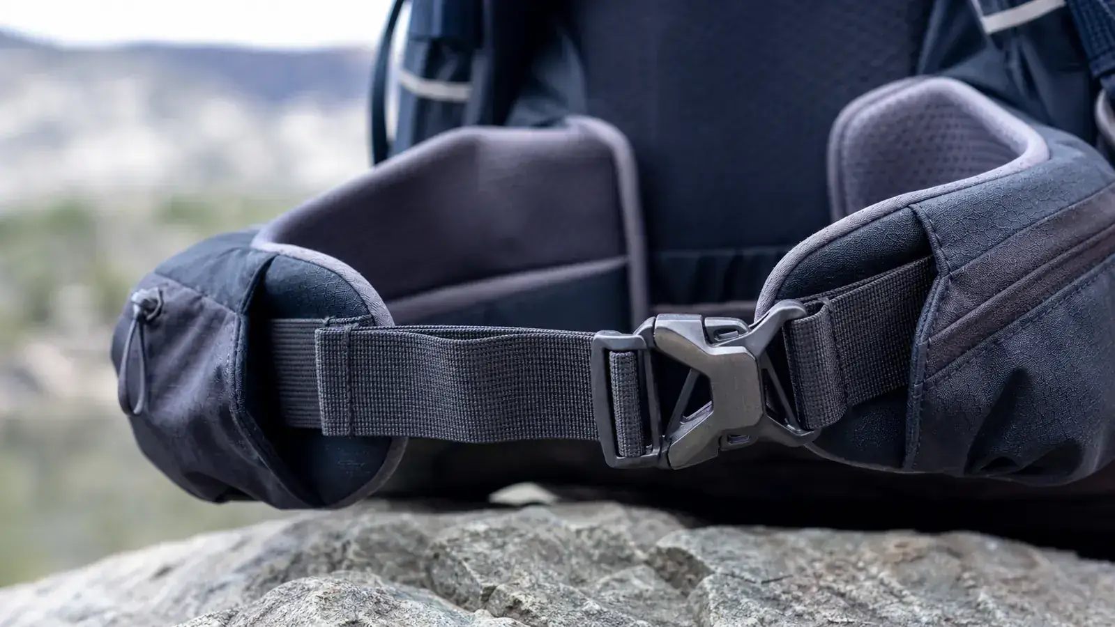 Hiker descending a wooded trail with a fully loaded 50L backpack